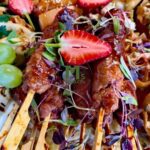 A rustic board or platter piled with sliders, wraps, skewers, and pitas for a bold meaty look.